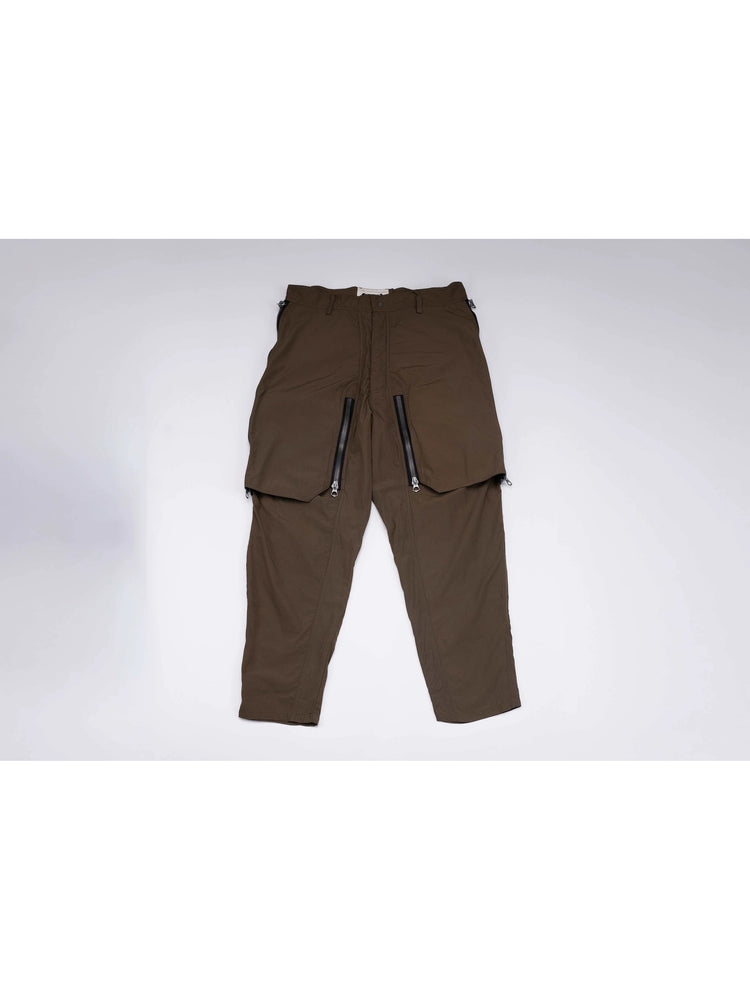 GAIA curved-blade technical pants in stone green — front garment-only view with curved zip panels closed