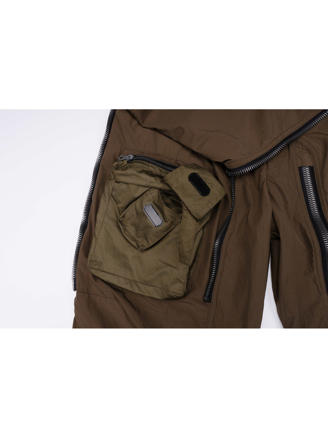 GAIA curved-blade technical pants in stone green — cargo pocket and zipper detail