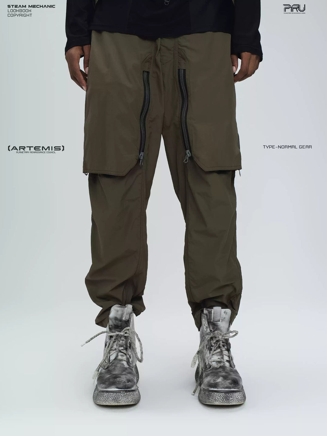 GAIA curved-blade technical pants in stone green — close modeled front view with the zip panels closed