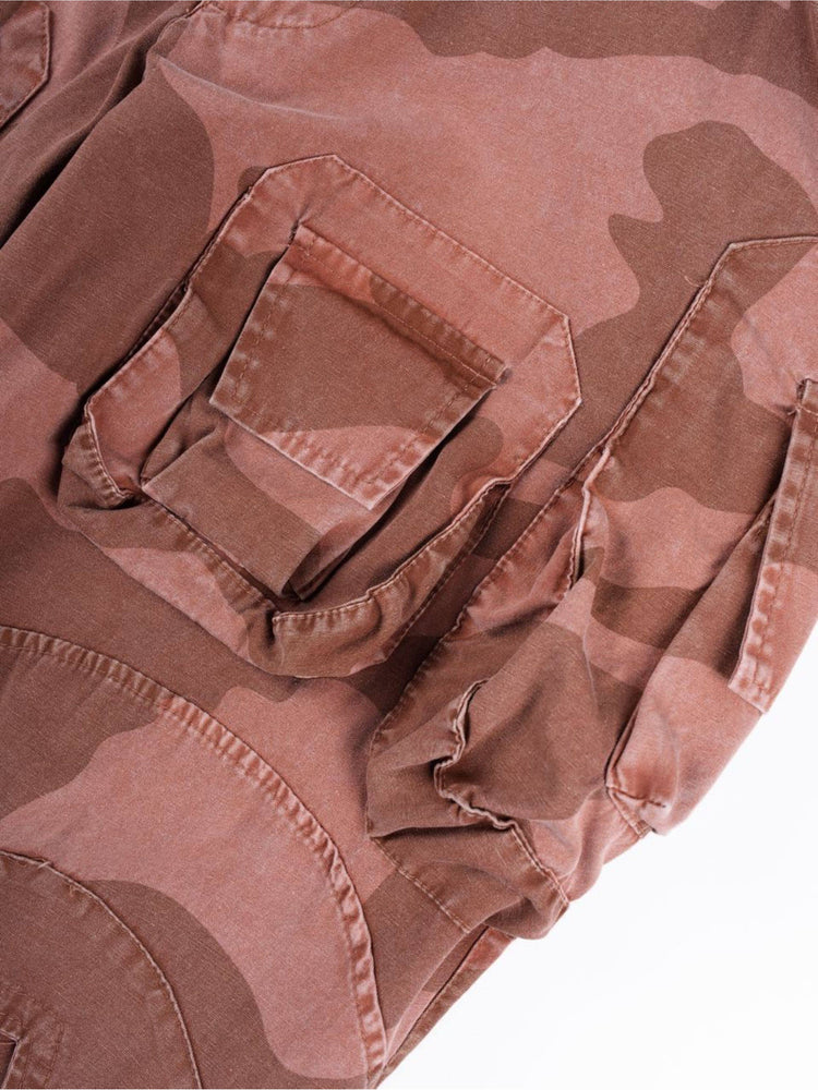 IXION washed camouflage combat pants in dune red — close-up of layered cargo-pocket construction
