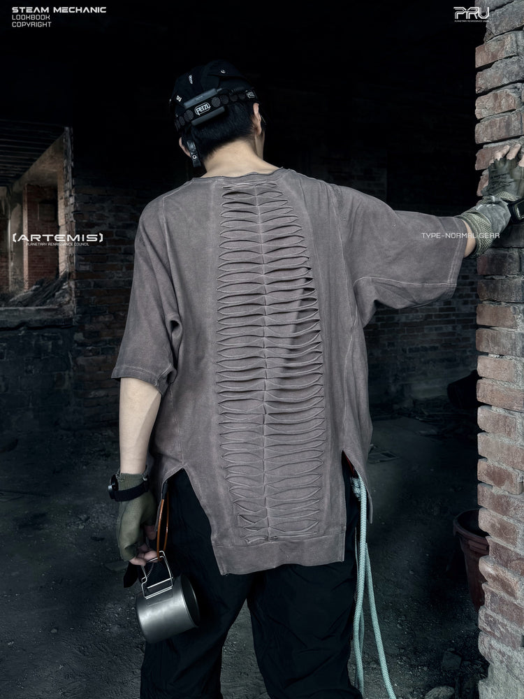 ERODED SPINE distressed asymmetric tee in wasteland vine brown — back modeled view with an arm raised and spine-like cutouts