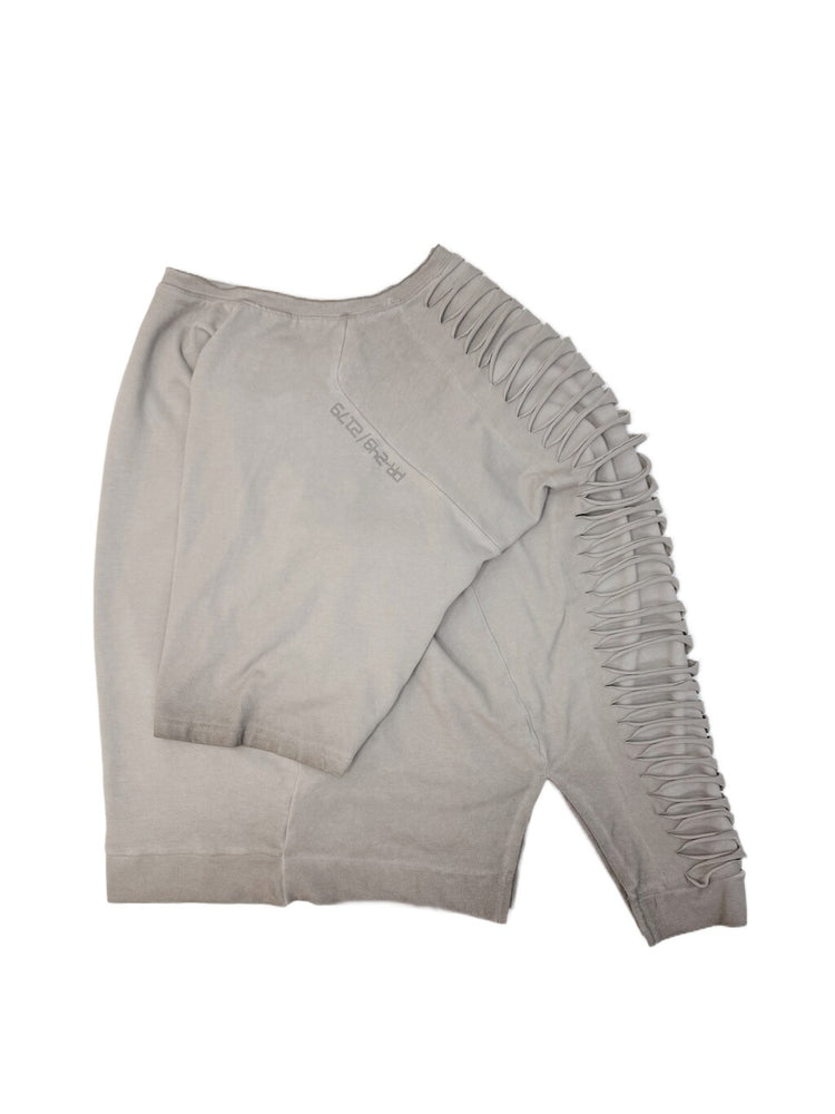 ERODED SPINE distressed asymmetric tee — folded oxidized white tee showing the back cutouts and washed texture