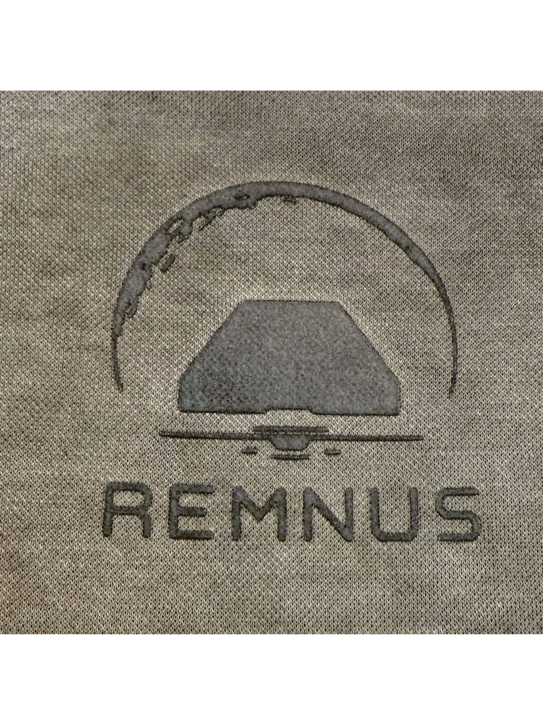 TWIN STAR lunar soil teal stretch riding base-layer top — close-up of the REMNUS chest print on lunar soil teal knit fabric