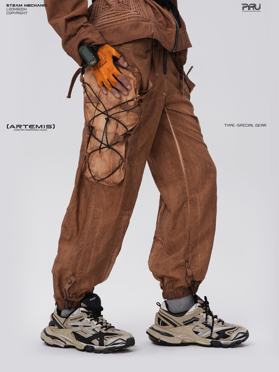 PIONEER detachable waist-pouch cargo pants in corona orange — side close-up with hand resting on the laced cargo pocket