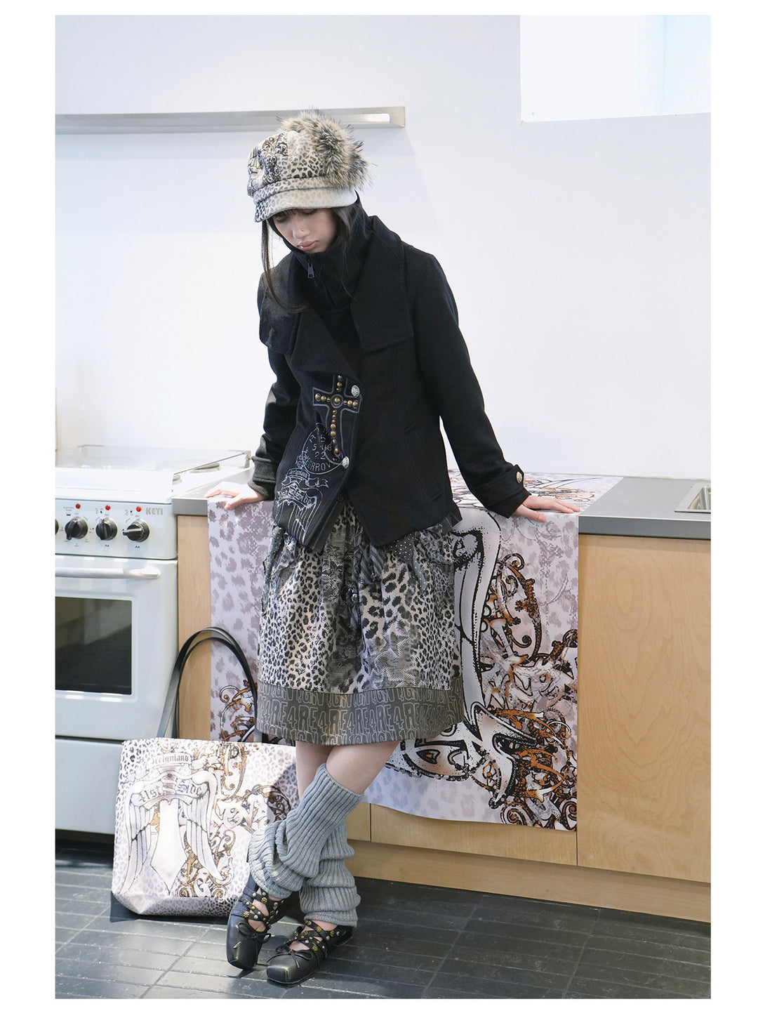 4RE1GN CROSS layered high-neck wool-blend jacket in black — three-quarter styled modeled view in a kitchen setting