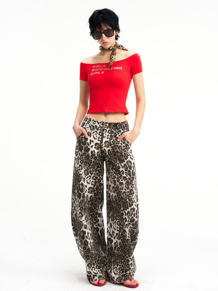 NEXT PASSPORT GIRLS SUPPORTING GIRLS rhinestone off-shoulder crop tee — red full-body modeled front view in leopard-print trousers.