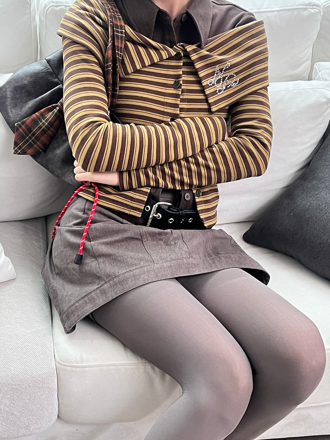 Close studio view showing the off-shoulder neckline and fitted striped knit cardigan