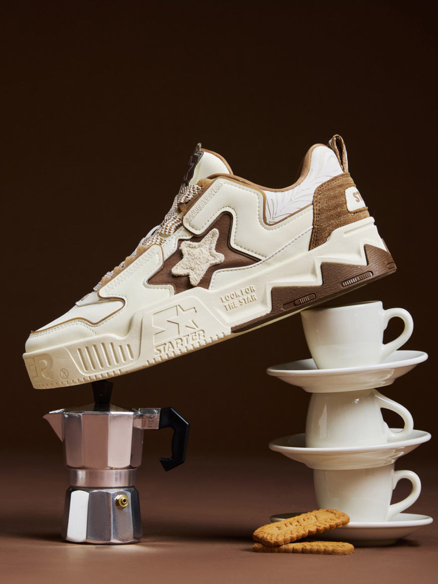 STARTER VOL 90S LATTE cream and brown sneaker balanced on coffee cups and a moka pot, showing its raised star and sculpted platform
