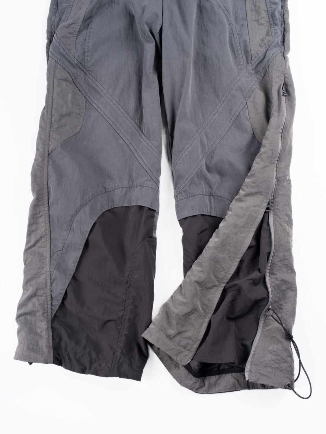 SUPERNOVA alloy gray metallic nylon technical pants — alloy gray lower-leg detail showing layered panels and adjustable zipped hems
