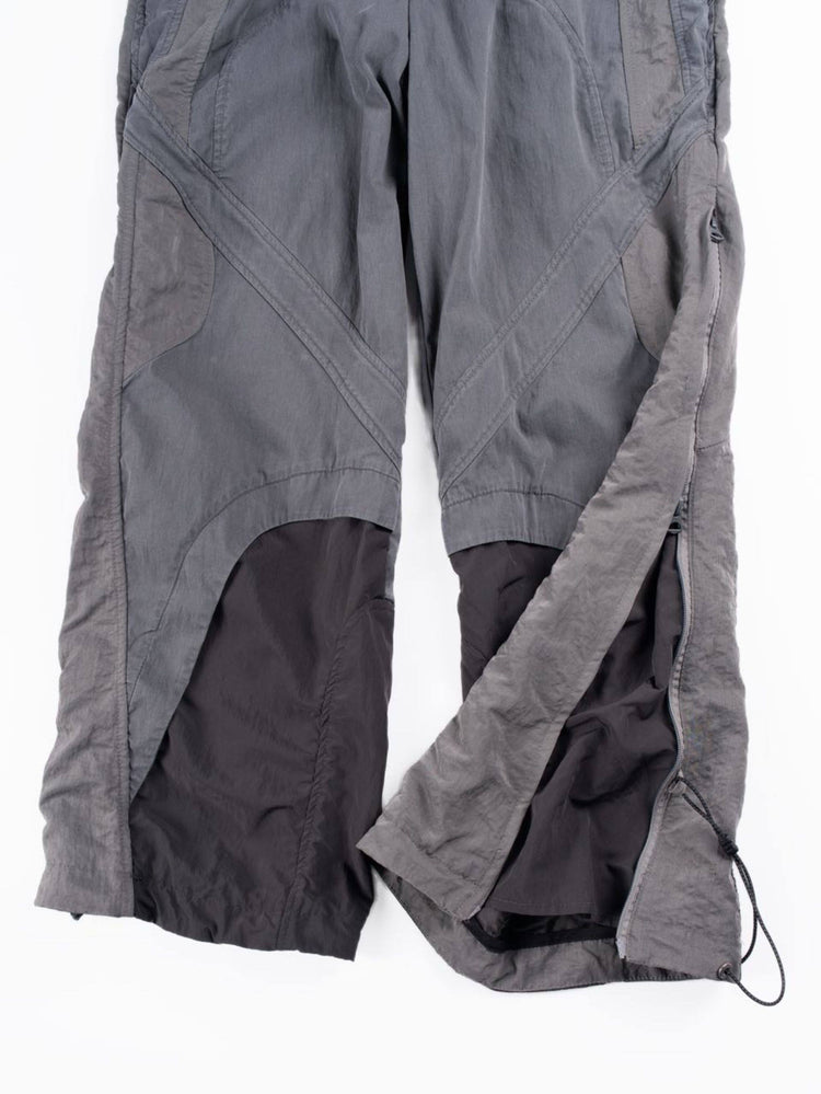 SUPERNOVA alloy gray metallic nylon technical pants — alloy gray lower-leg detail showing layered panels and adjustable zipped hems