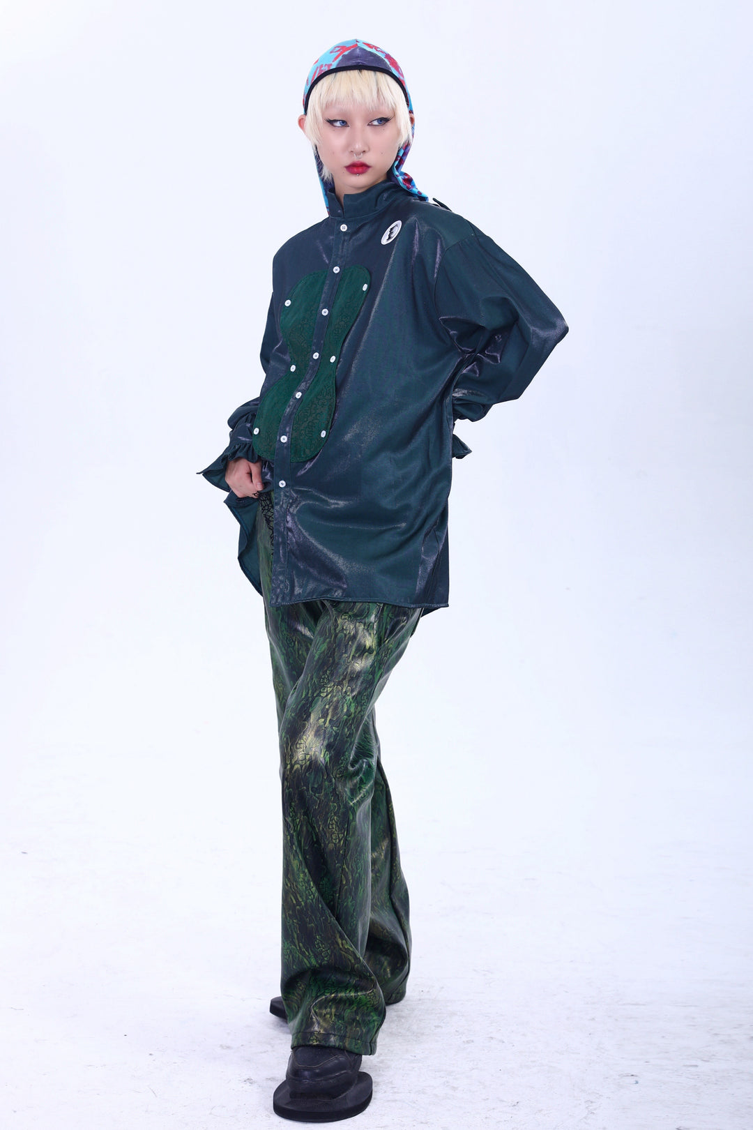 EMBRYO TRIANGLE ARMOR lace-inset leather pants in green — front modeled outfit with hands behind the green overshirt