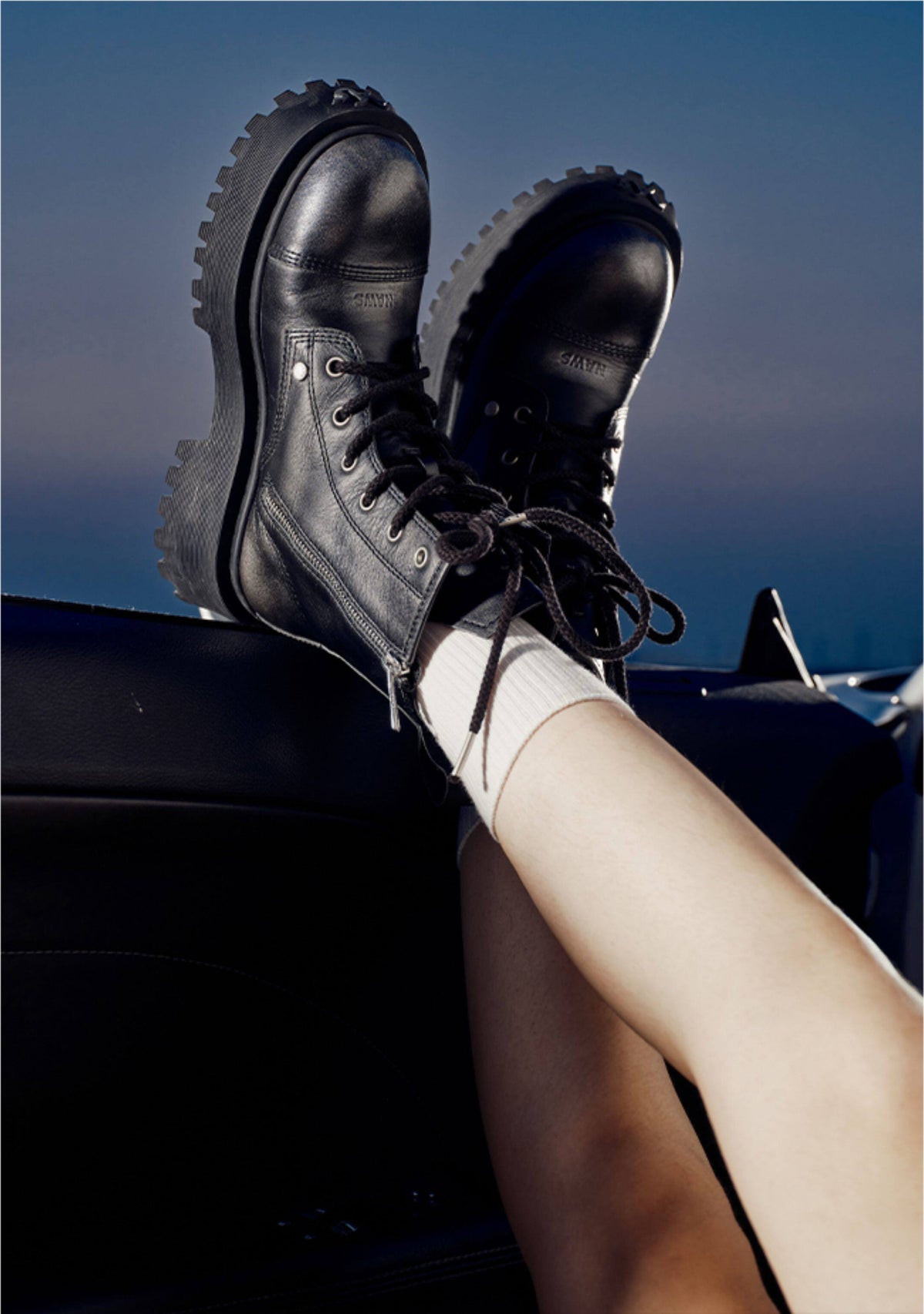NAWS KNIGHT leather platform lace-up boots in black — nighttime styled view with the model’s feet raised beside a car.