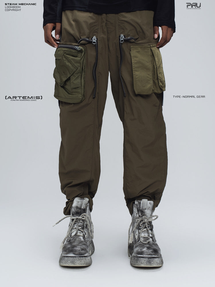 GAIA curved-blade technical pants in mountain green — front modeled view with the utility pouches exposed