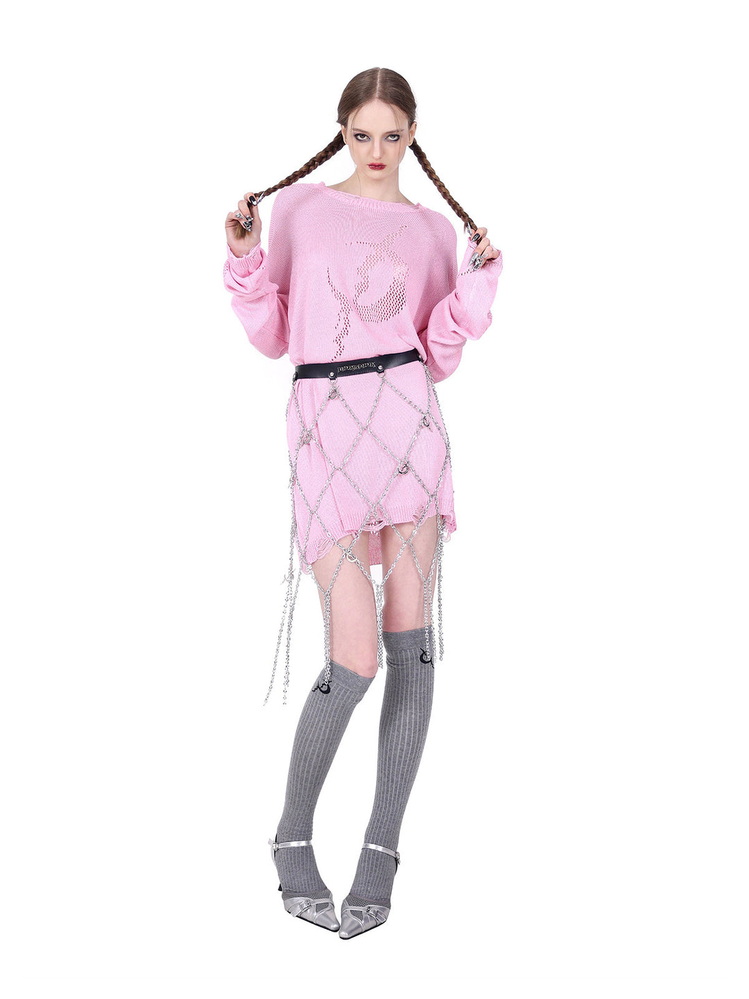 PINKSPINK ELECTRIC MOON distressed open-knit sweater in pink — front modeled pose with braids held apart and a separate chain belt