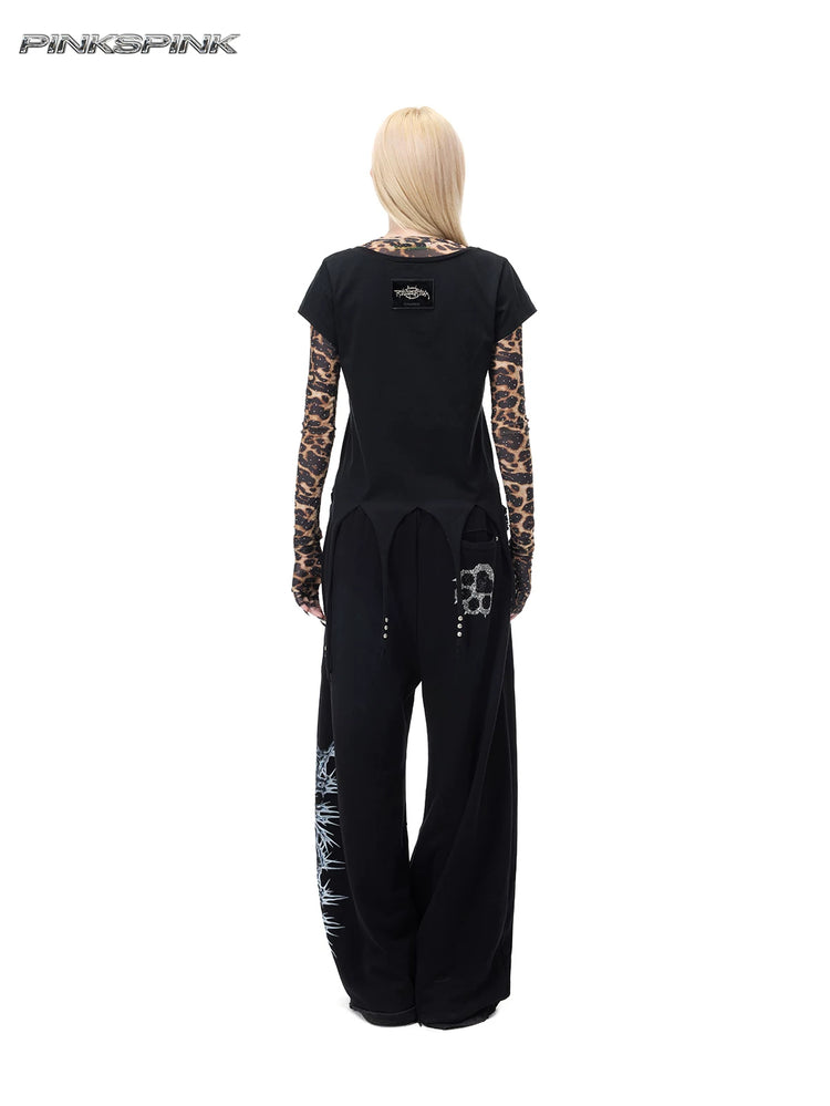 PINKSPINK PUNK CACTUS studded pointed-hem tee in black — full-length rear modeled view over a separate leopard mesh layer and black trousers
