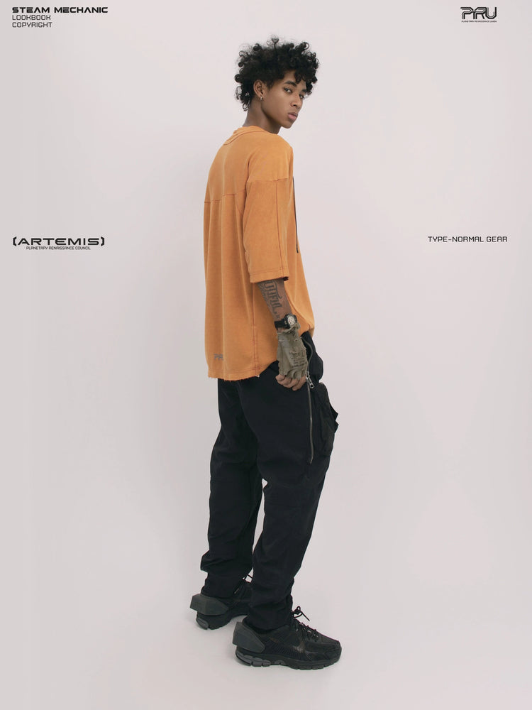 LIGHTSHADOW eclipse orange deconstructed technical tee — full-length side view with head turned toward the camera