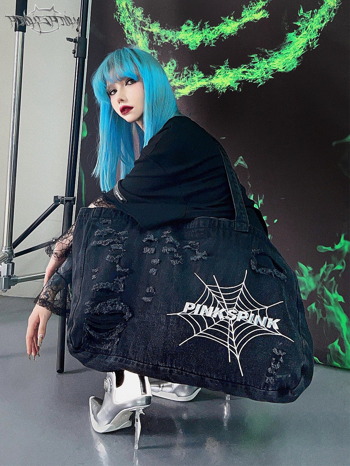 PINKSPINK SPIDER distressed denim shoulder tote — seated modeled view showing the web logo and distressed denim