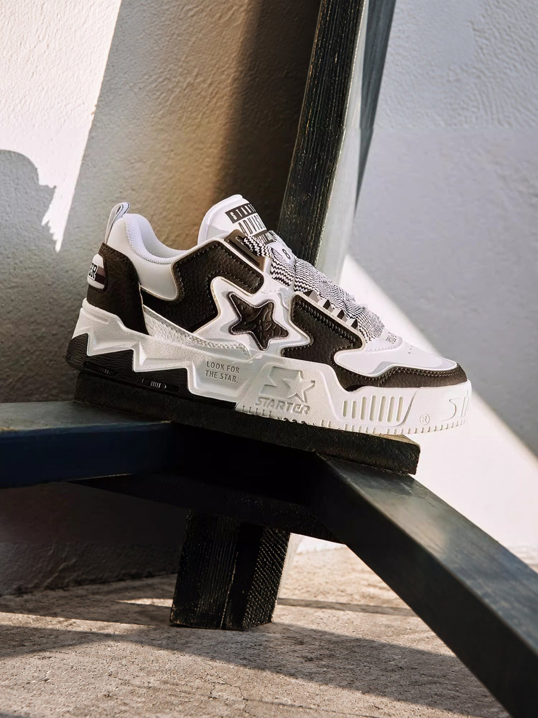 STARTER VOL 90S Panda Black sneaker on a metal chair, close-up of the star panel, patterned laces and platform sole