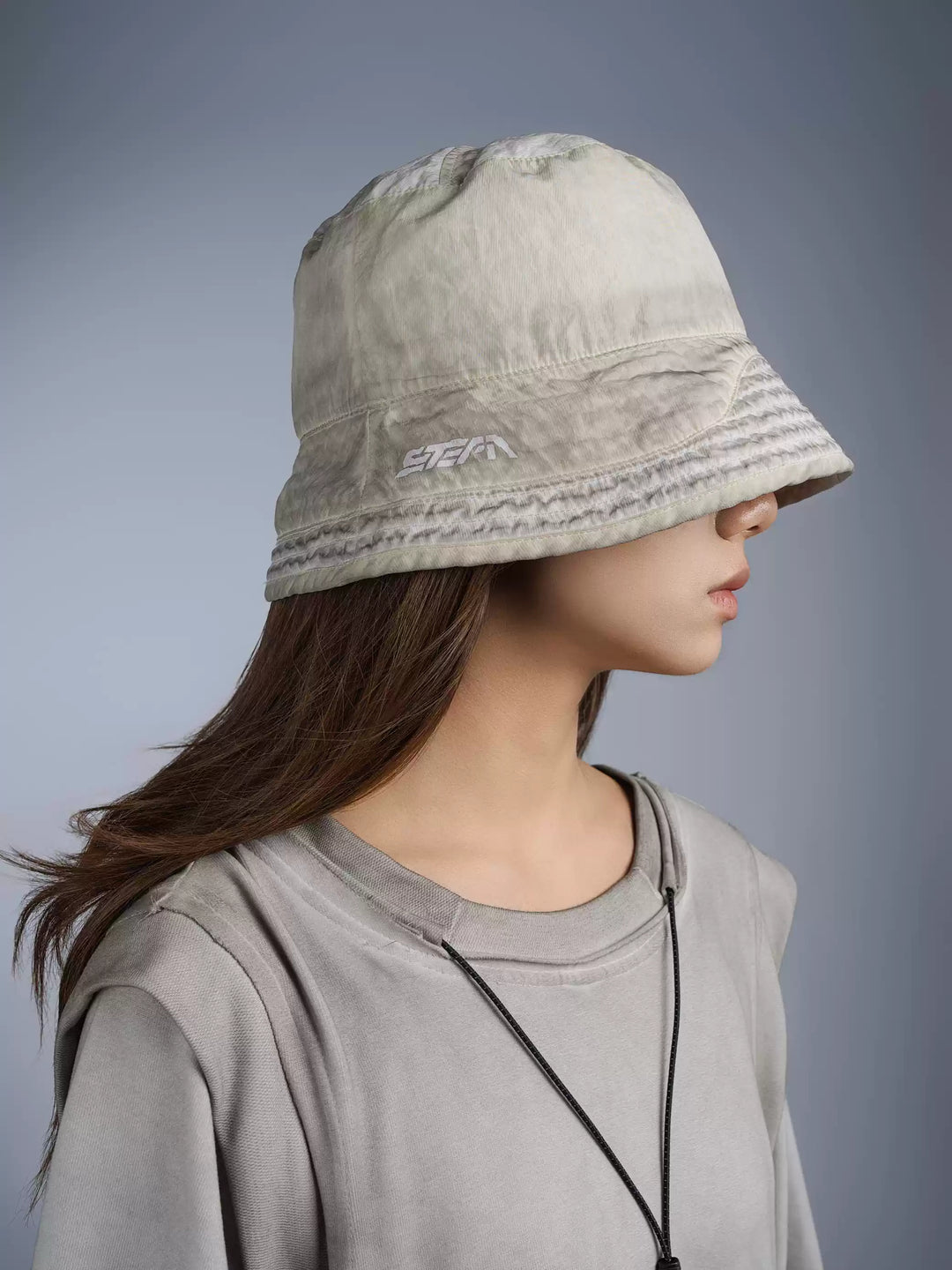 PIONEER eris white distressed nylon bucket hat — modeled close-up showing the washed finish and embroidered STEAM logo