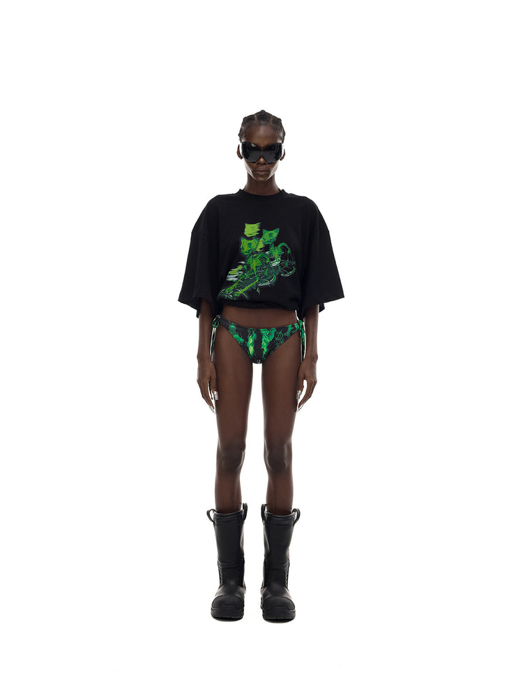 PINKSPINK MONSTER cat-skeleton oversized graphic tee in black — centered full-length front modeled view with the hem rolled up over separate printed bottoms