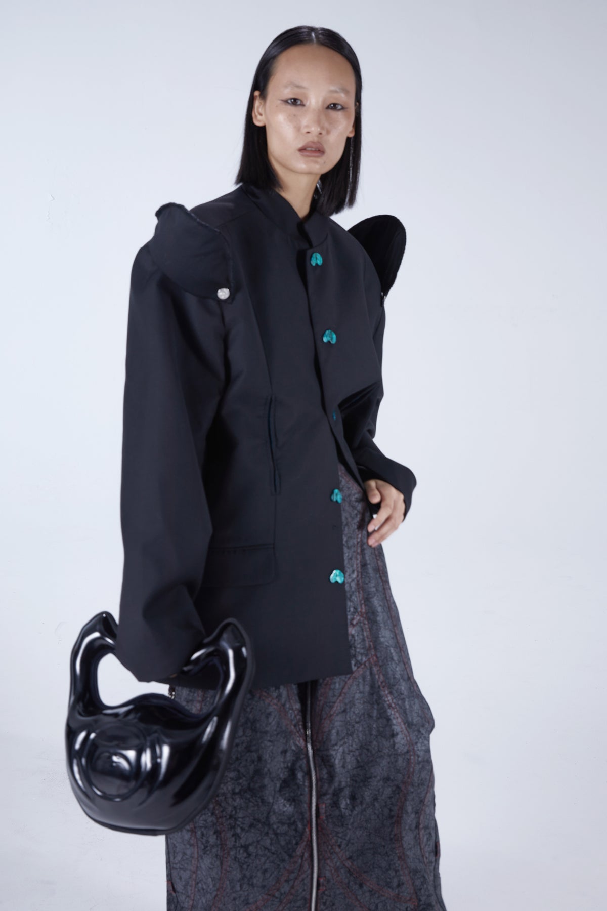 EMBRYO IMPERIAL GUARD detachable-shoulder Zhongshan blazer in black — close modeled view holding a black sculptural bag