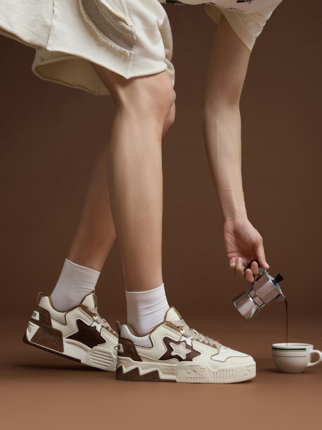 STARTER VOL 90S LATTE on-foot side and inner-side views beside a coffee cup, with intact wide laces and contrasting heel panels