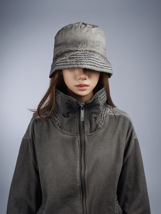 PIONEER distressed nylon bucket hat in moon dust gray — front modeled portrait with the brim framing the face