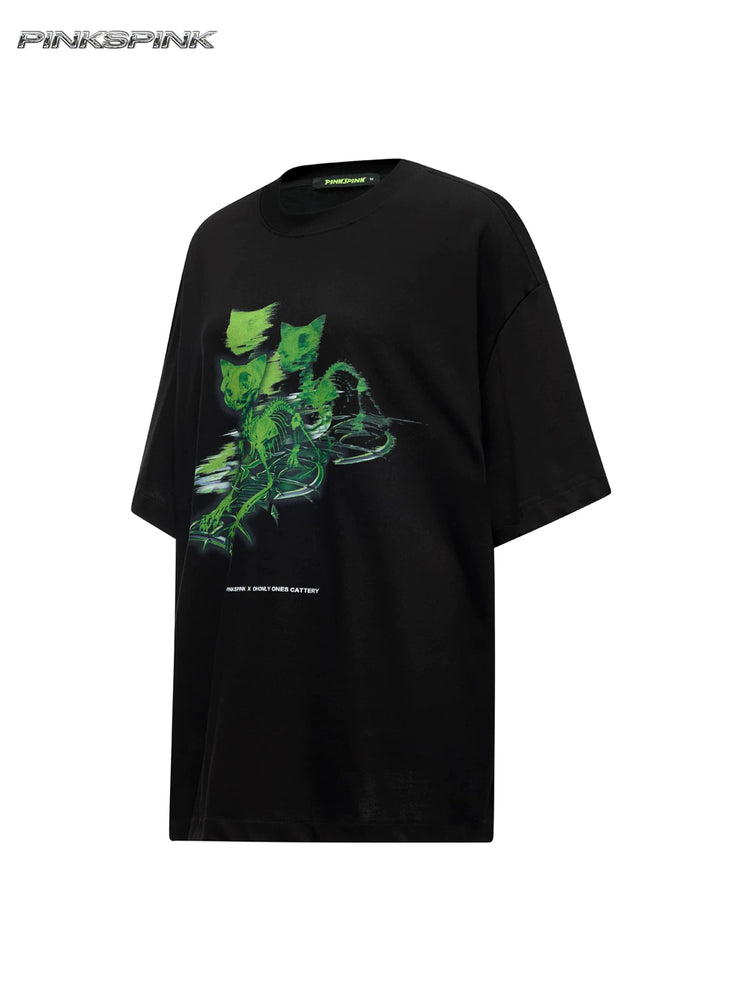PINKSPINK MONSTER cat-skeleton oversized graphic tee in black — angled garment-only front view showing the green graphic and oversized cut