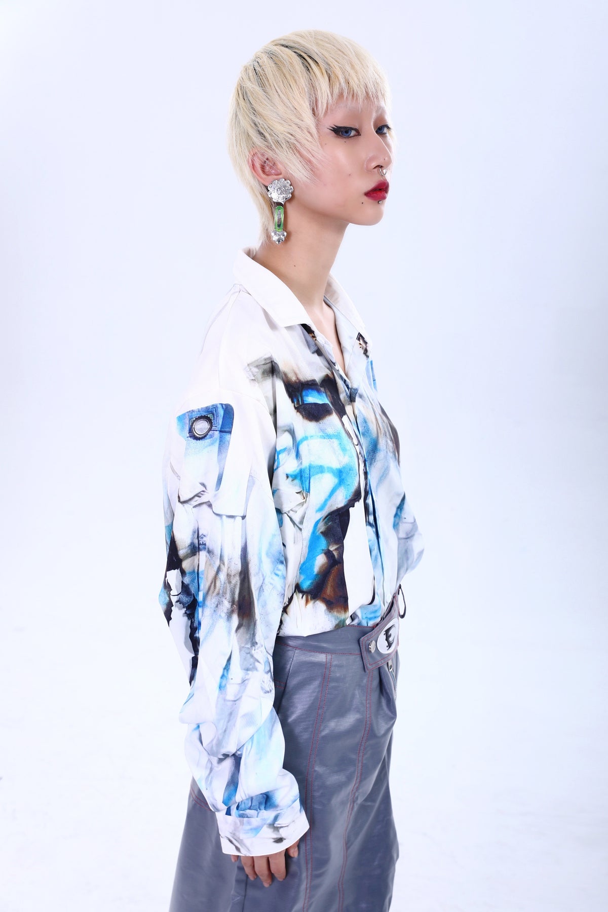 EMBRYO RUYI detachable sculptural earrings in silver — modeled with an abstract-print shirt, three-quarter view