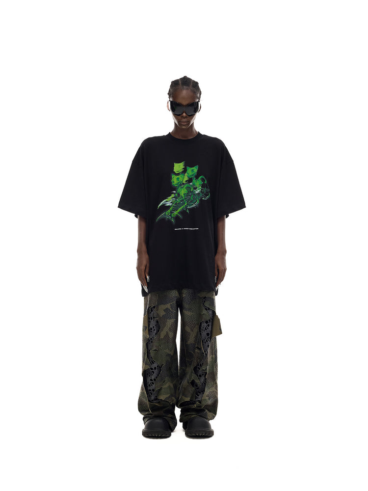 PINKSPINK MONSTER cat-skeleton oversized graphic tee in black — straight-on full-length front modeled view over separate camouflage trousers