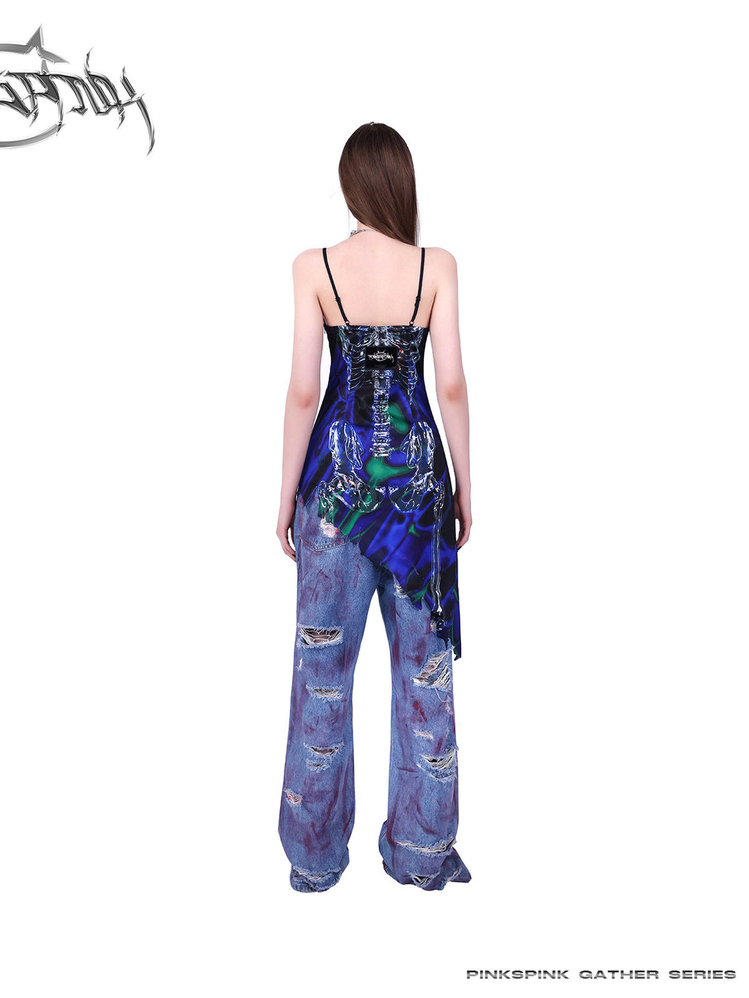 PINKSPINK COSMOS skeleton-print asymmetric slip dress in blue green multicolor — rear full-length modeled view layered over jeans
