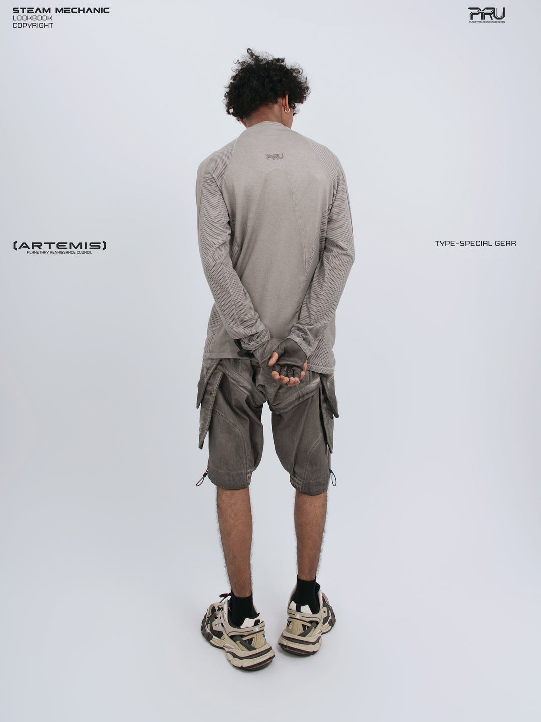 STARCORE mesh-panel long-sleeve top — full-length back view with hands clasped behind