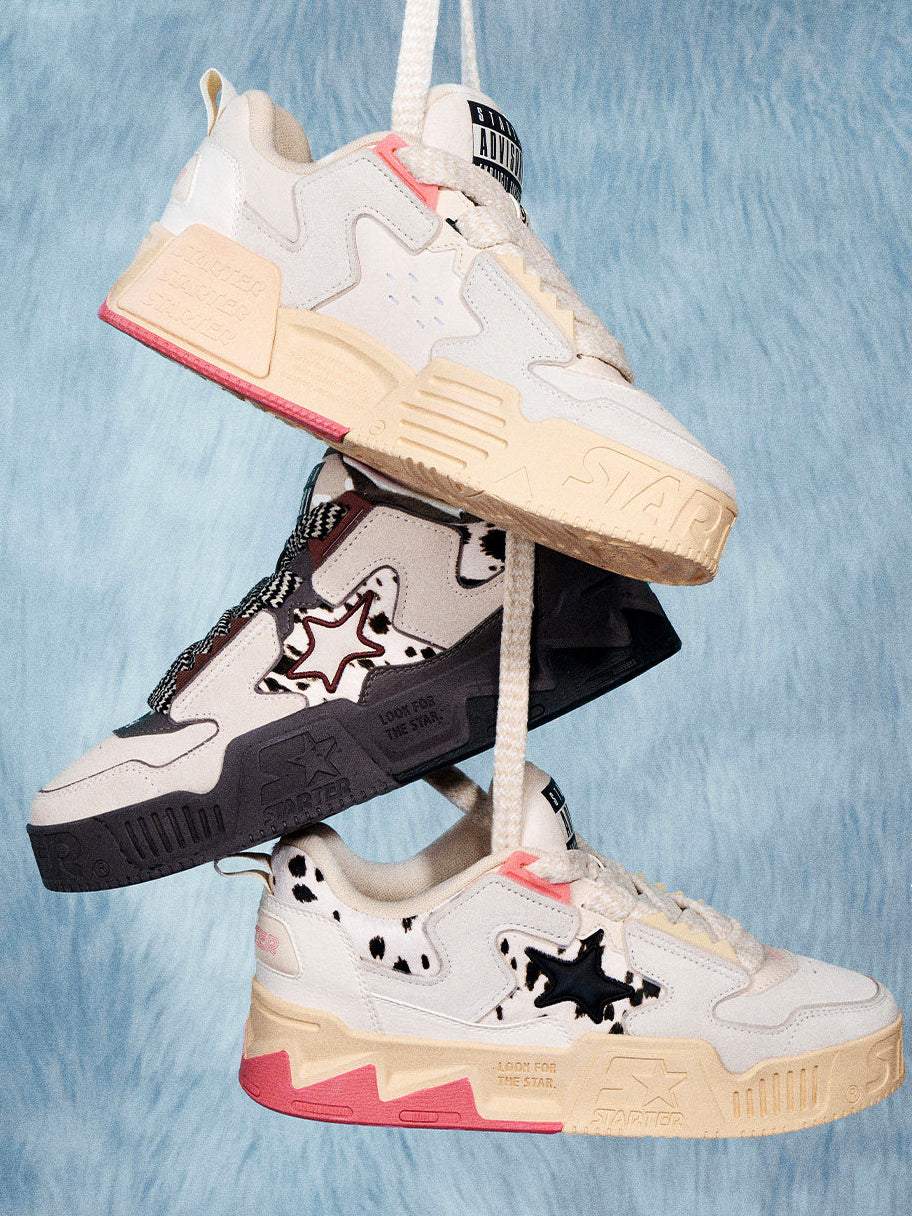 STARTER ZOO Cow Pink inner and outer sides hanging above and below a separate Zebra Gray sneaker on a blue background
