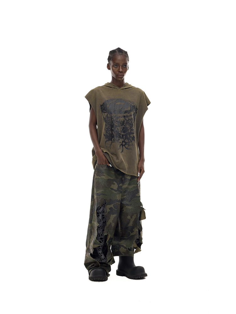 PINKSPINK COSMOS washed sleeveless hooded tee in olive green — three-quarter front full-length modeled view holding the hem