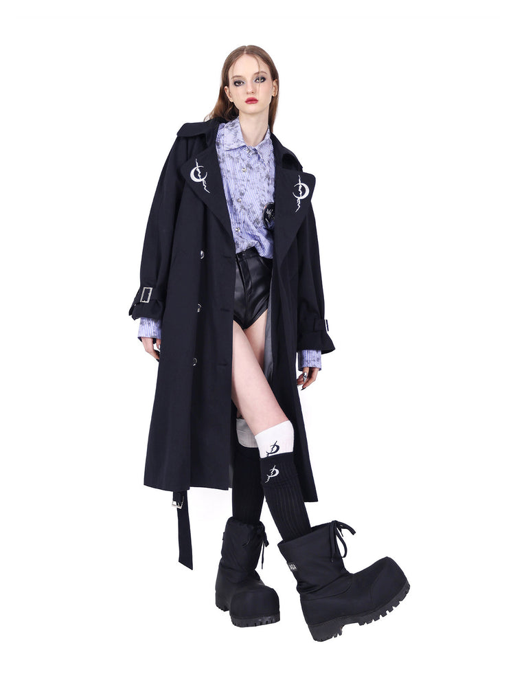 PINKSPINK REBEL ring-pierced faux-leather hotpants in black — front angled styling view with an open trench and bent knee