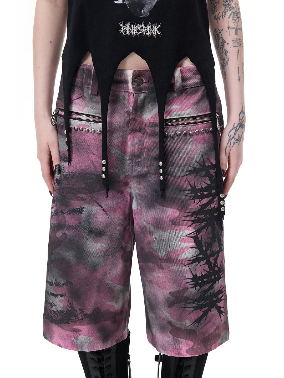 PINKSPINK PUNK CACTUS studded pointed-hem tee in black — close-up of the pointed hem and metal studs above separate pink camouflage shorts