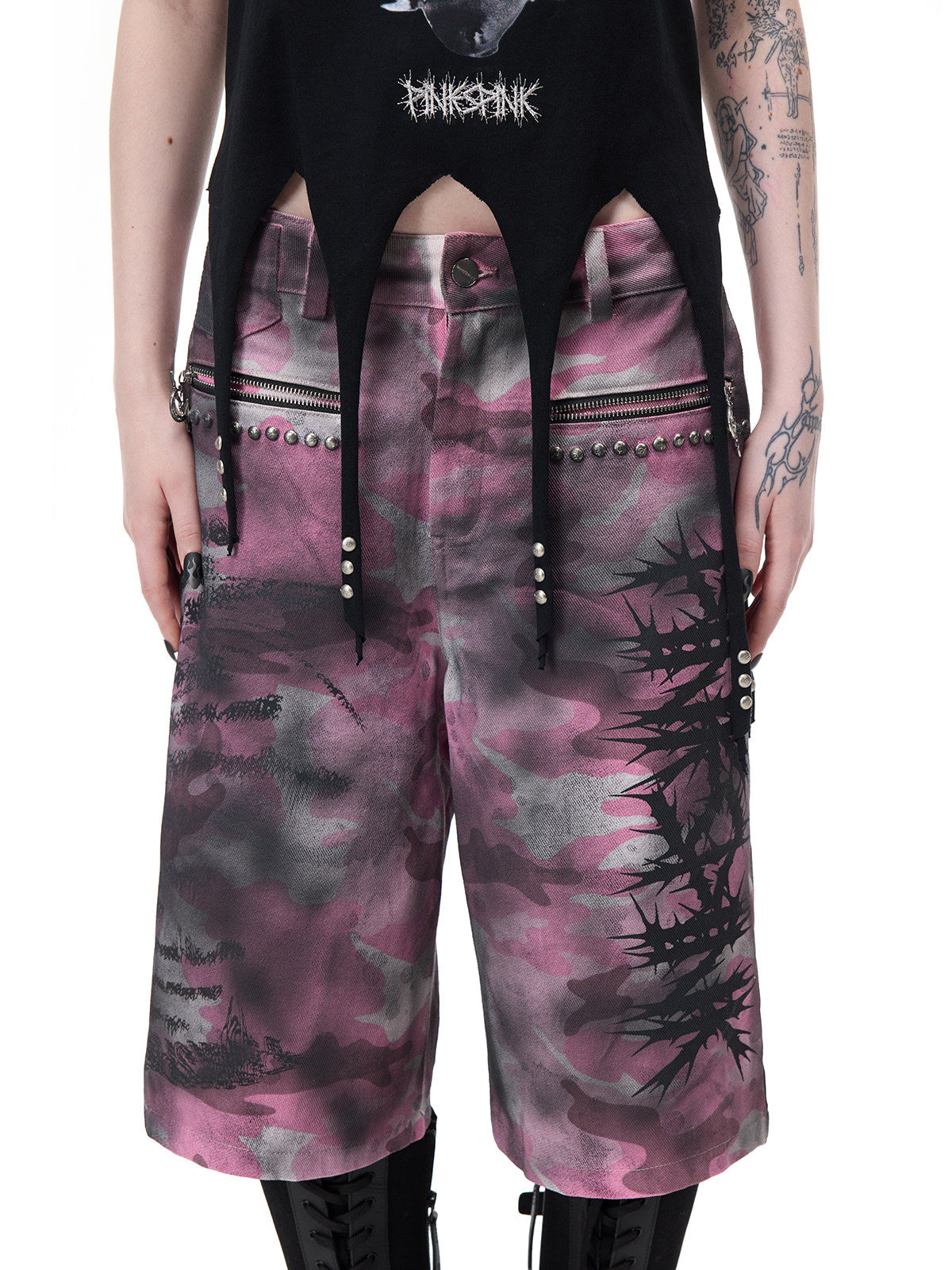 PINKSPINK PUNK CACTUS studded pointed-hem tee in black — close-up of the pointed hem and metal studs above separate pink camouflage shorts
