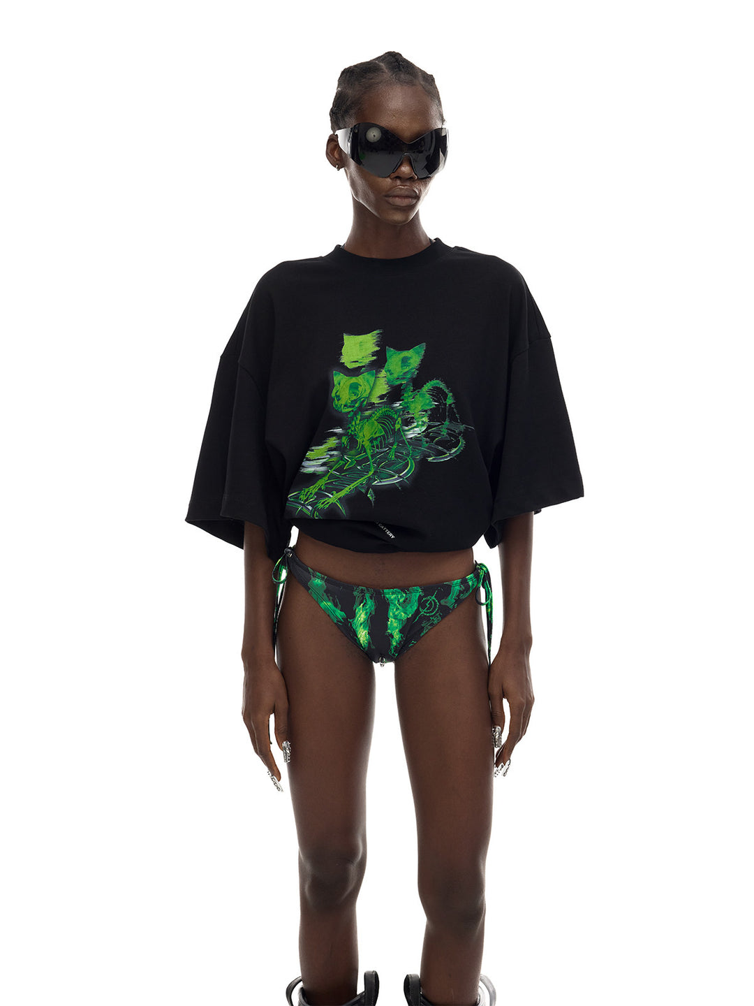 PINKSPINK MONSTER cat-skeleton oversized graphic tee in black — three-quarter front modeled view with the hem rolled up