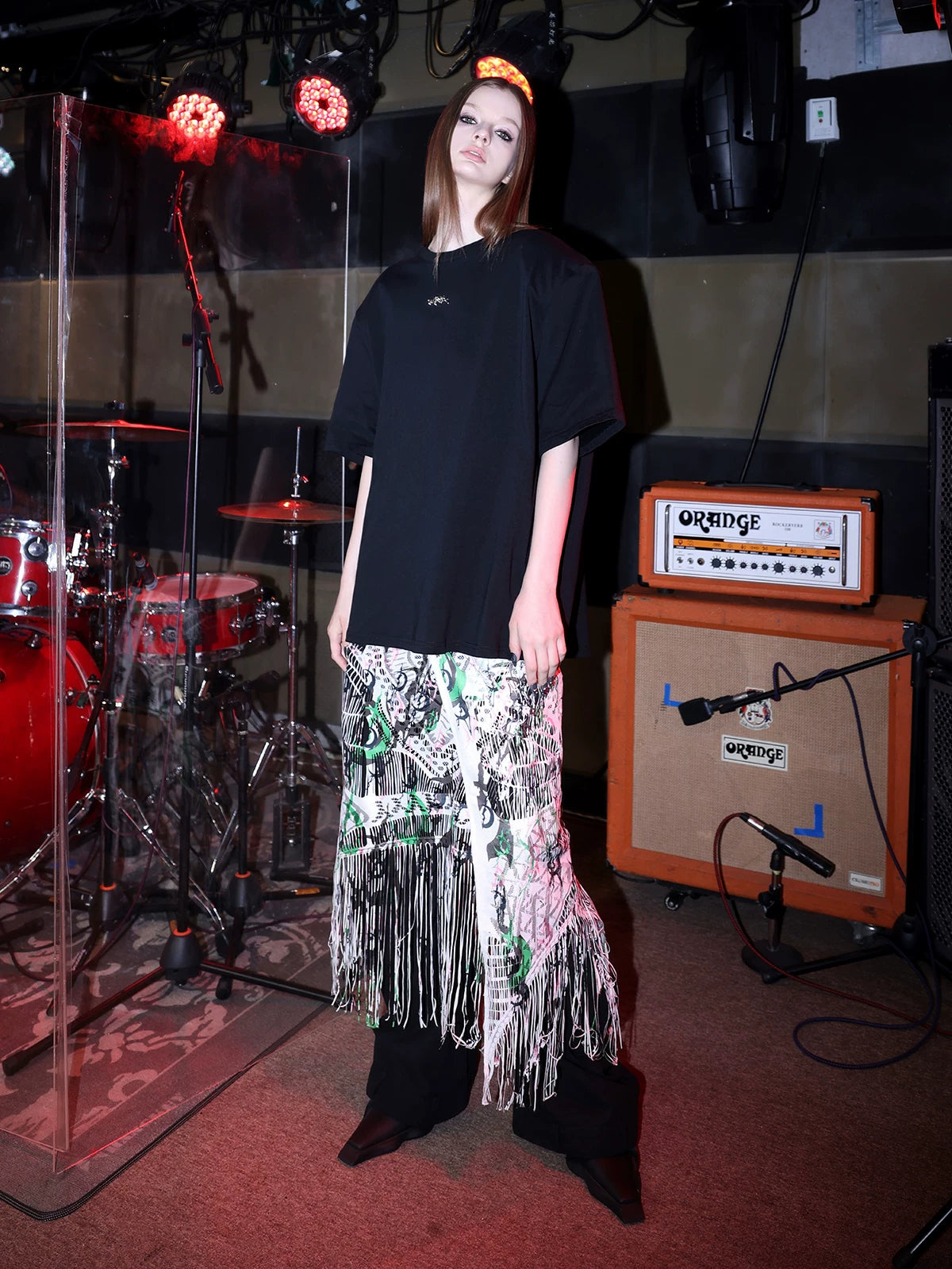 PINKSPINK SHRED SIGNAL printed fringe layering apron — white multicolor — three-quarter view layered below an oversized tee