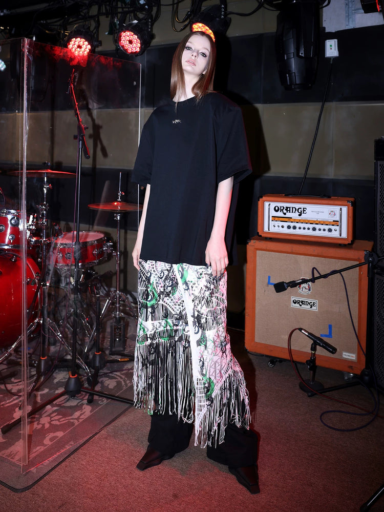PINKSPINK SHRED SIGNAL printed fringe layering apron — white multicolor — three-quarter view layered below an oversized tee