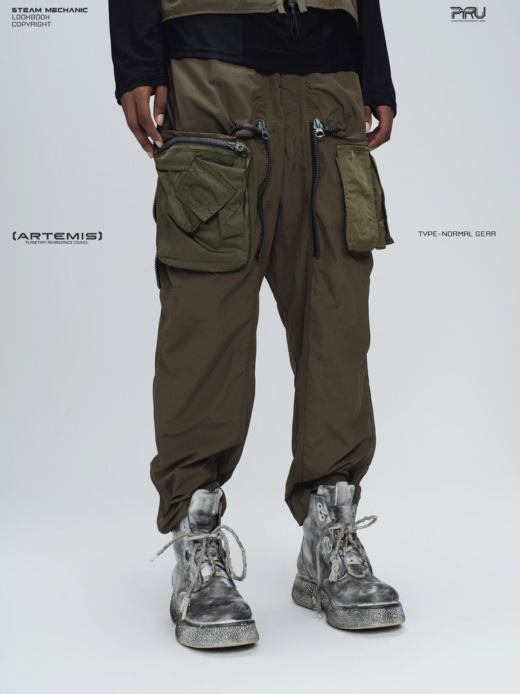 GAIA curved-blade technical pants in mountain green — angled modeled view of the exposed utility pouches