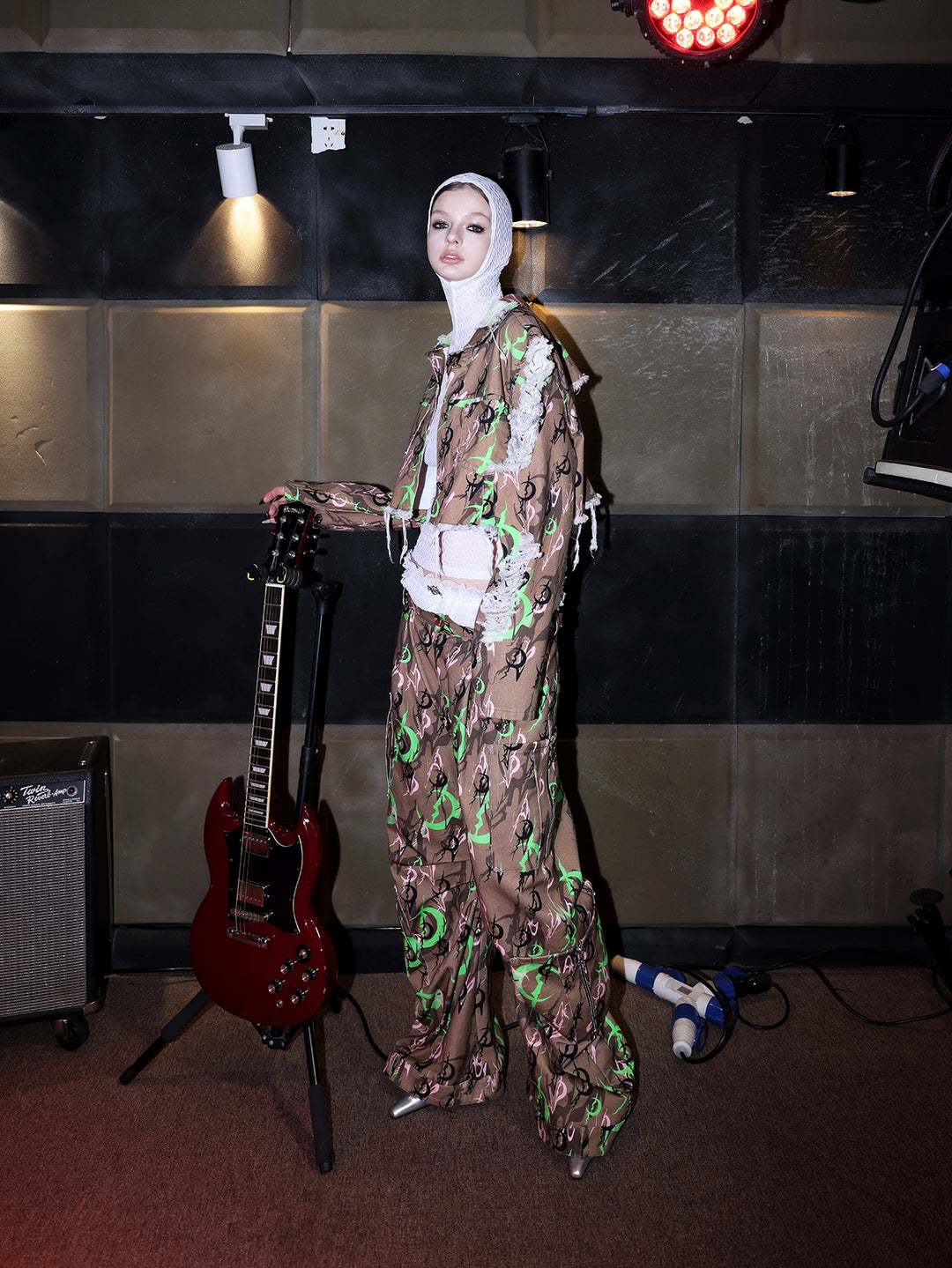 PINKSPINK ELECTRIC MOON distressed camo cropped jacket in CAMOUFLAGE — full-body side view beside a guitar.