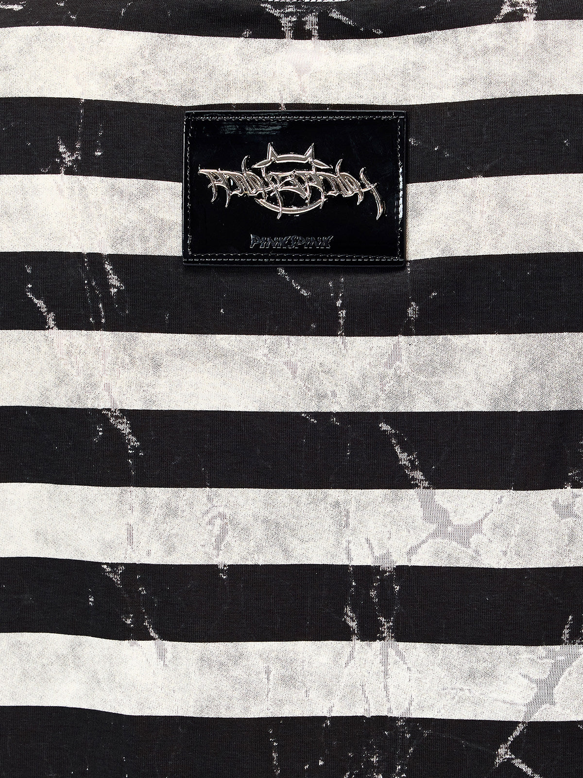 PINKSPINK STATIC asymmetric striped burnout long-sleeve tee in black and white — macro close-up of the raised metallic back badge and distressed striped fabric