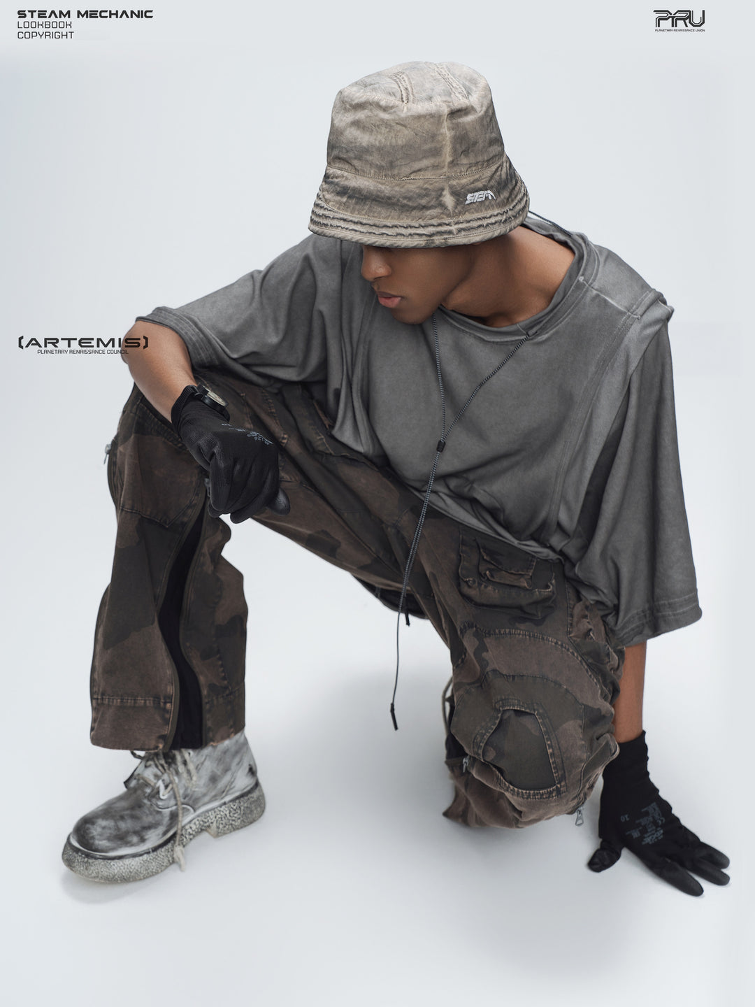 PIONEER distressed nylon bucket hat — crouching modeled view of the mercury brown hat