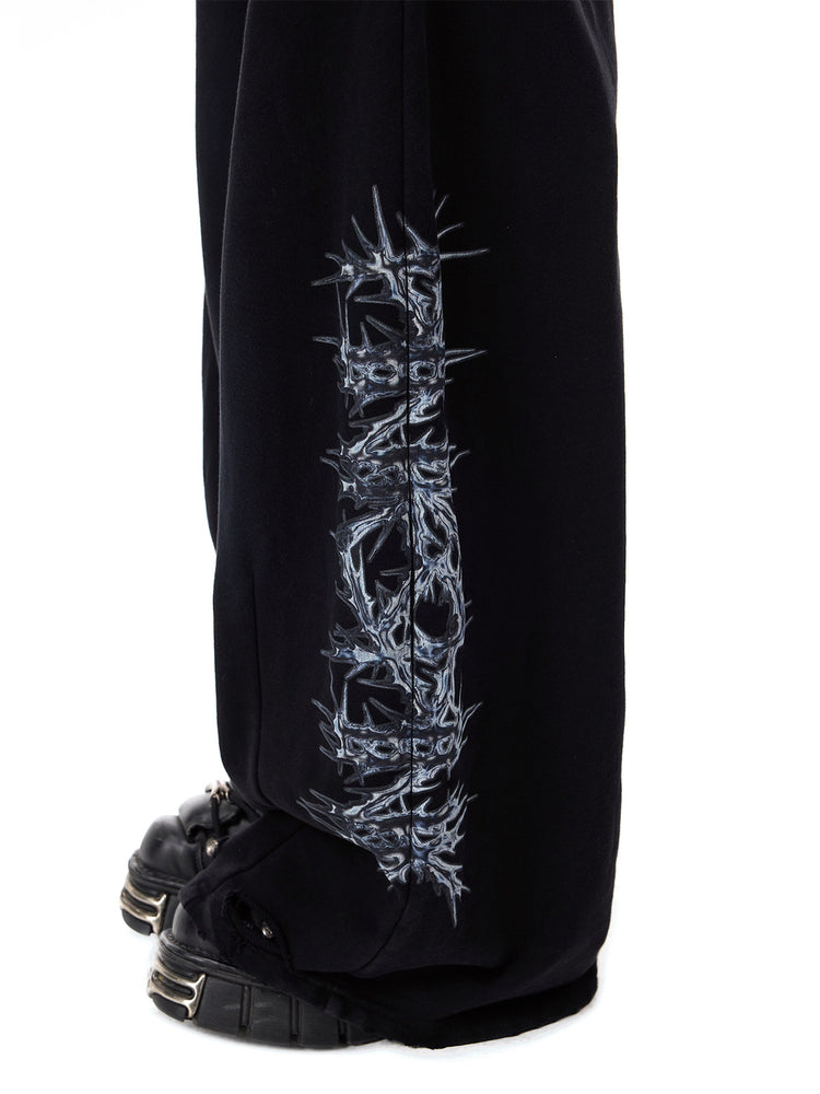 PINKSPINK CATPAW rhinestone curved-leg sweatpants in black — close lower-leg detail of the thorn print and distressed hem