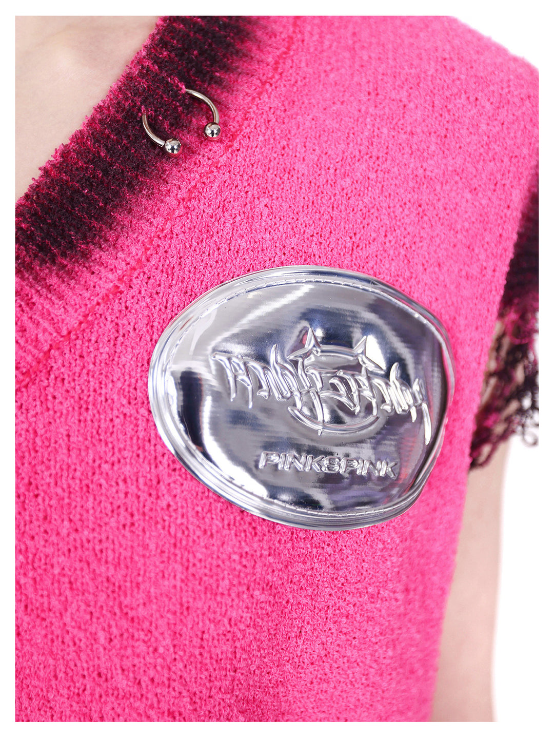 PINKSPINK REBEL distressed ring-detail knit vest in pink — macro close-up of the metal neckline ring and raised silver-tone brand badge