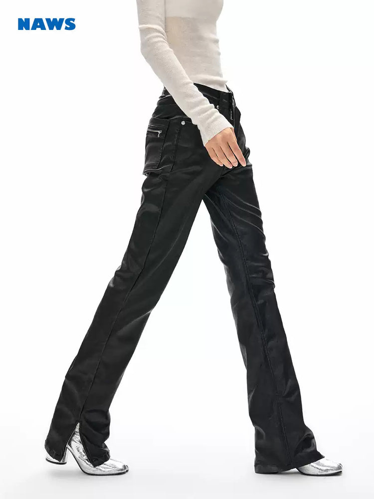 NAWS wax-coated zip-hem jeans in BATIK BLACK — walking side view showing the long straight-leg silhouette.