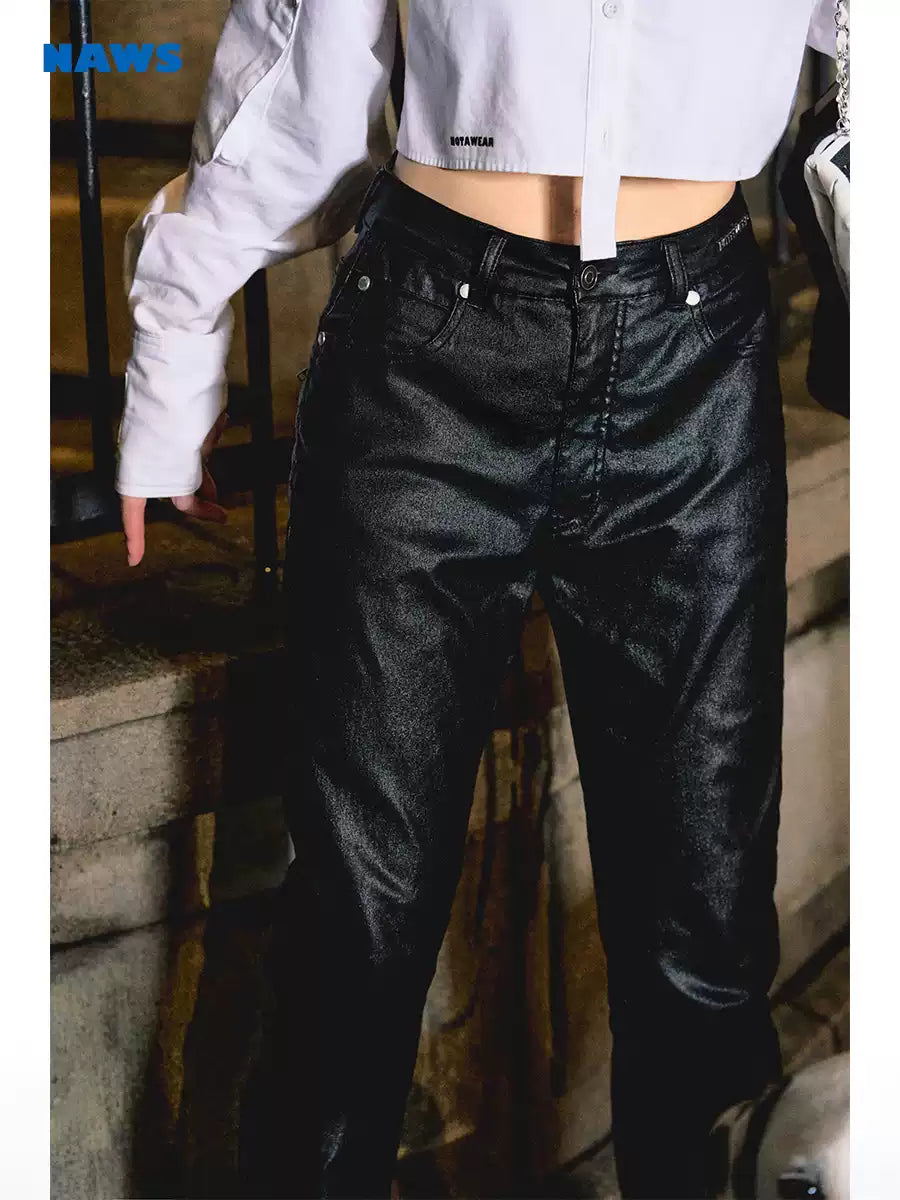 NAWS wax-coated zip-hem jeans in BATIK BLACK — indoor waist-and-leg detail modeled with a cropped white shirt.