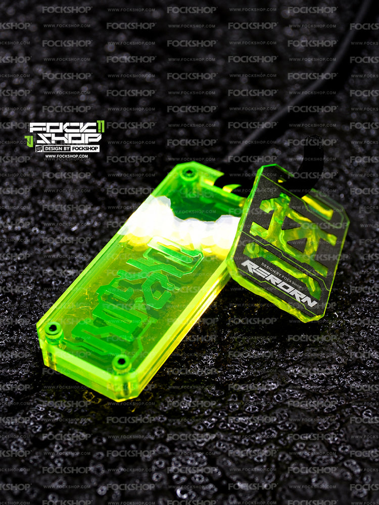 FOCKSHOP REBORN talisman charm — angled fluorescent-green detail with reflected studio light and braided cord