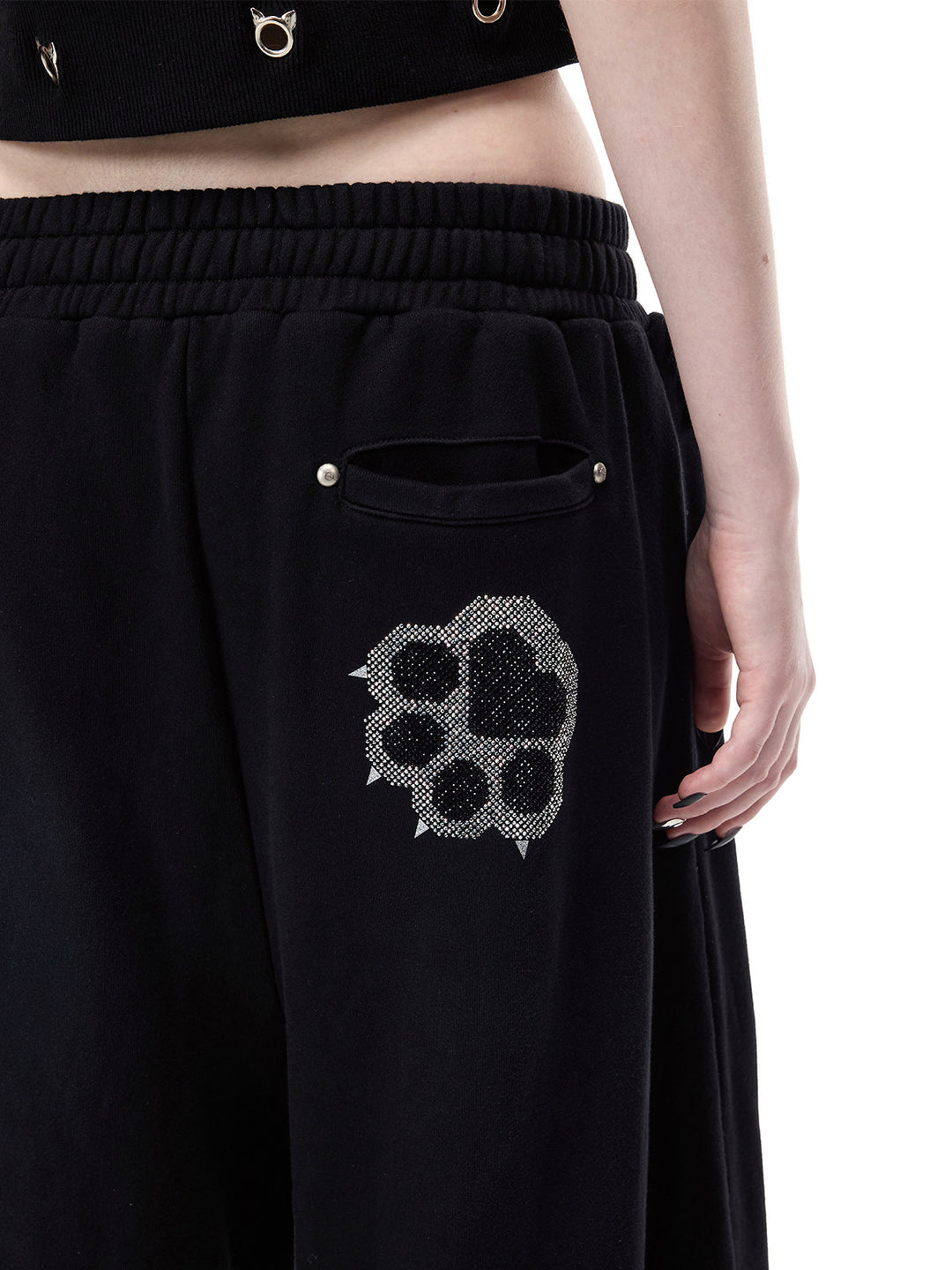 PINKSPINK CATPAW rhinestone curved-leg sweatpants in black — close rear detail of the pocket opening, studs and rhinestone paw